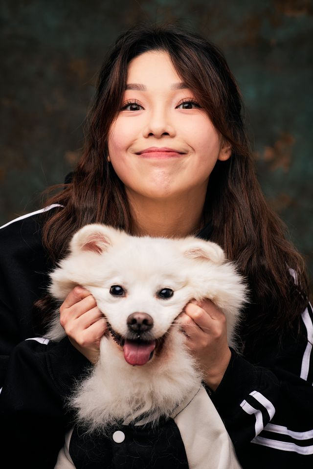 An owner smiling while holding her white pomeranian